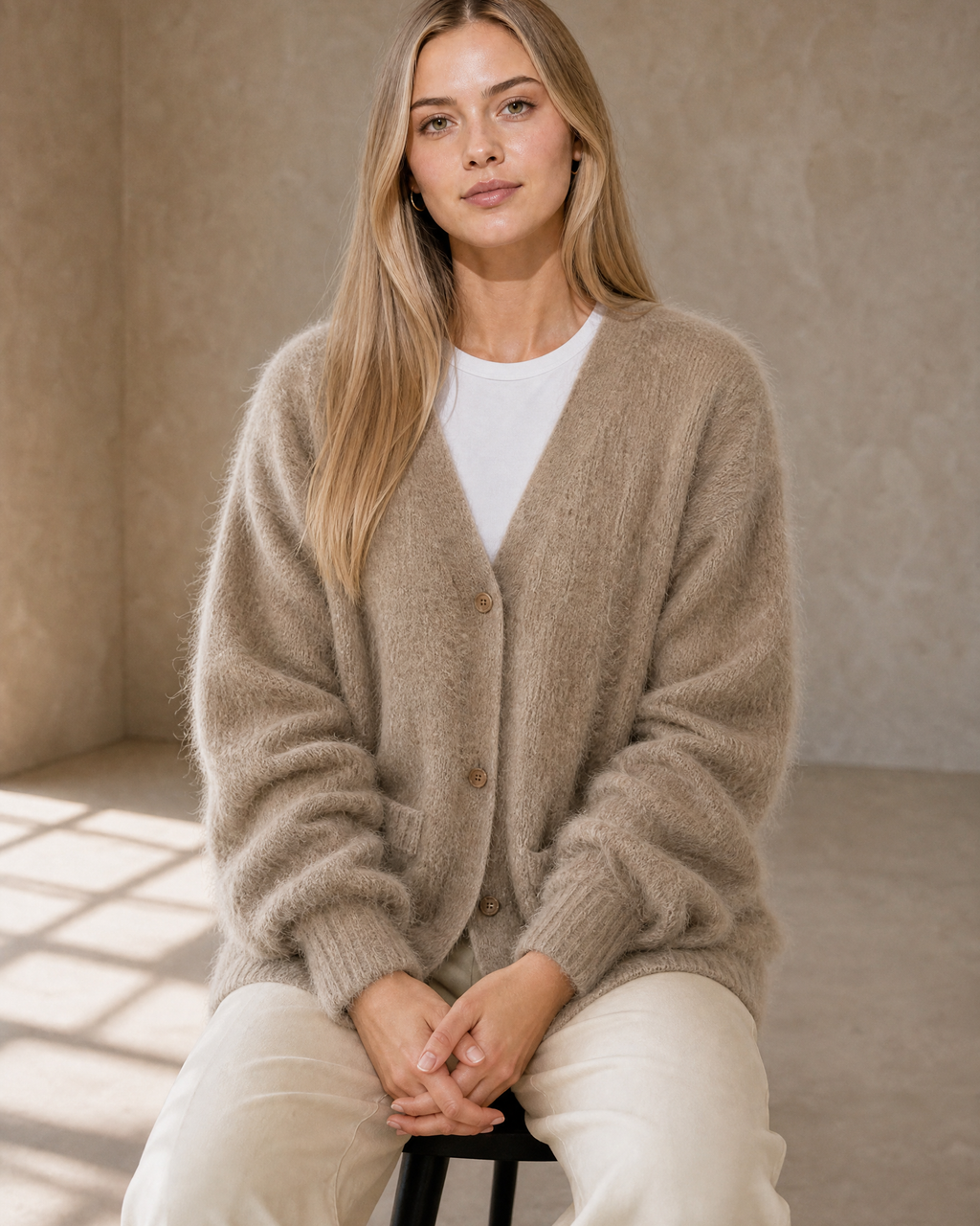 Women's V-Neck Button Cardigan with Pockets in Khaki, stool, hands in lap, worn by model